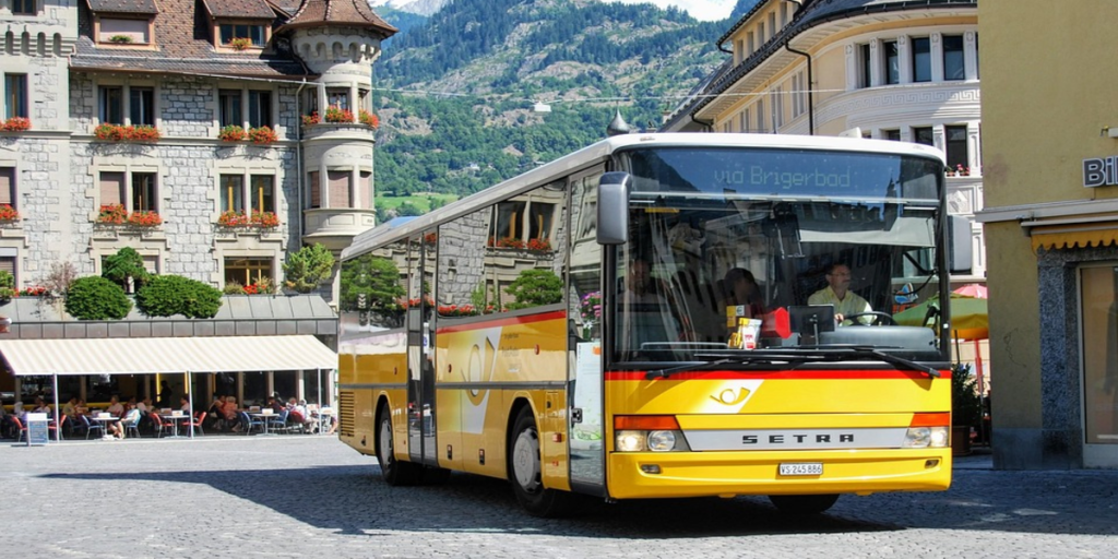 Autobús amarillo en ruta por los Alpes suizos en una zona rural