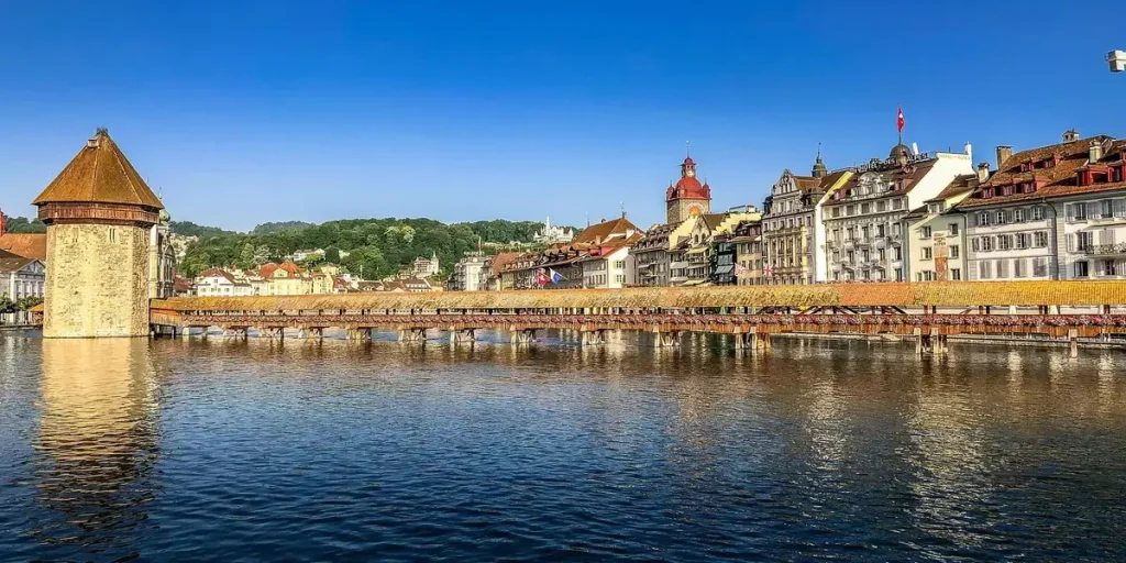 Vista del puente de la Capilla en Lucerna, Suiza, con la torre del agua reflejada en el río Reuss bajo un cielo despejado