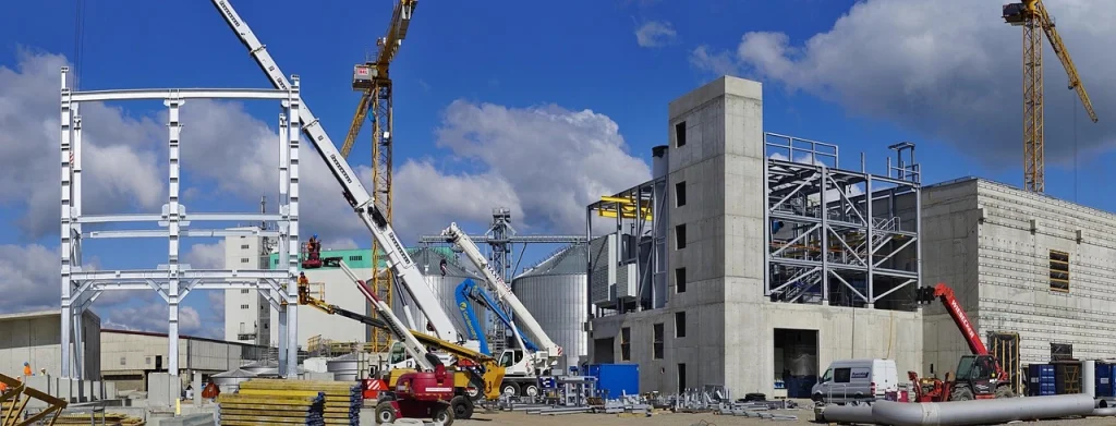 Obrero de la construcción con casco y chaleco de seguridad trabajando en el andamio de un edificio en Suiza, un sector con oportunidades laborales.